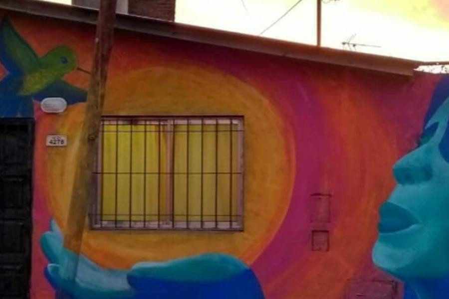 Mural de una mujer y un colibrí sobre la fachada de una vivienda