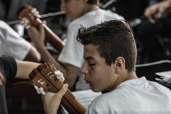 Jóvenes tocan la guitarra en la Escuela de Música